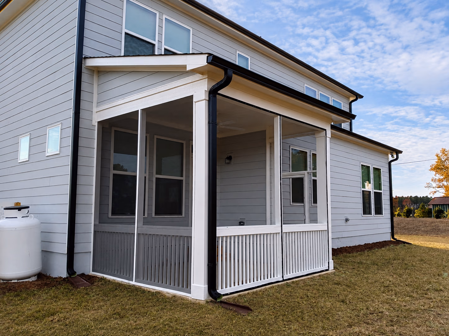 White house with a screened porch and grassy yard under a partly cloudy sky.